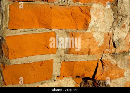 Eine detaillierte Ansicht einer strukturierten orangen Ziegelwand mit sichtbarem Mörtel. Stockfoto