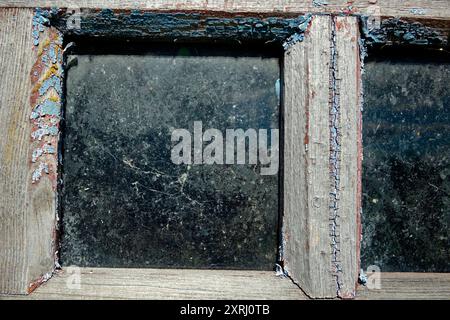 Detaillierter Blick auf ein rustikales Scheunenfenster mit altem Holz und staubigem Glas. Stockfoto