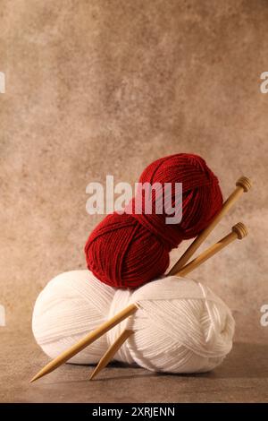 Zwei weiche Garnstränge und Stricknadeln auf hellbraunem Hintergrund Stockfoto