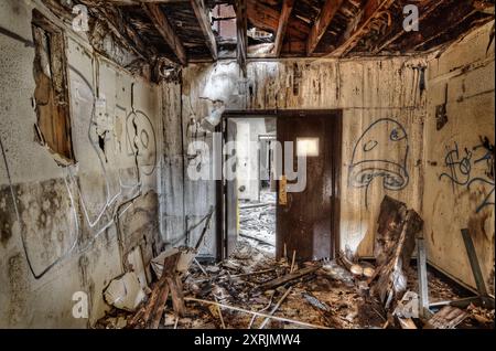 Abblätternde Farbe, zerbröckelnde Wände, Graffitis und ein teilweise eingestürztes Dach heben den Innenraum auf der verlassenen Marinestützung von Mare Island hervor. Stockfoto