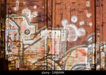 Alter, verlassener und rostiger Eisenbahnwagen, bedeckt mit Graffiti. Auffällige, farbenfrohe Formen und abstrakte Komposition. Alte Graffiti-bedeckte Alterungsbahn. Stockfoto