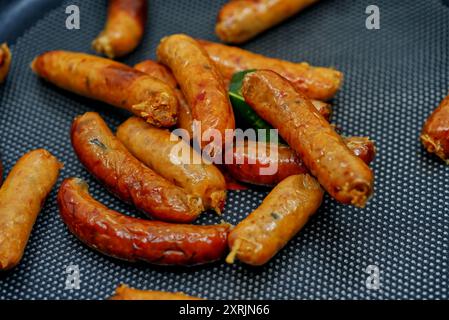 Sai Oua, die traditionelle thailändische Nördliche Wurst, die kleine Art von Sai Oua auf schwarzem Pfannenbraten, Haufen von thailändischen Nördlichen Würstchen, Nahaufnahme Lebensmittelbild Stockfoto