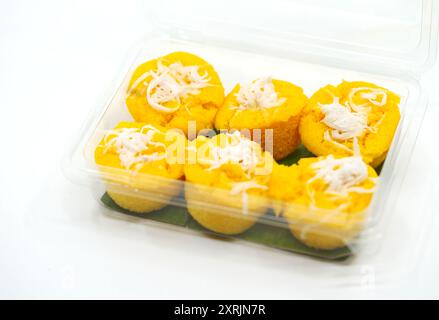 Gesund ein thailändisches Dessert namens Kanom Tan oder Toddy Palm Cake mit Kokosnussschnitzel. Der gelbe Toddy Palm Kuchen in einer Plastikverpackung auf weiß Stockfoto