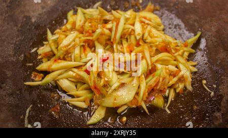 Sambal Mangga oder Chili Sauce gemischt mit geschnittenen jungen Manggofrüchten servieren Sie auf traditionellem Mörtel und Stößel . Authentisch typisch für indonesische scharfe Chili Stockfoto