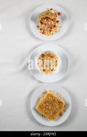 Traditionelle arabische Süßigkeiten (Kunafa, Othmaliye, umm ali) auf weißem Hintergrund. Draufsicht, Kopierraum Stockfoto