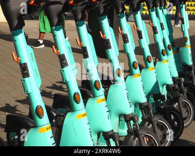 Reihe von hellgrünen West Scoot Elektrorollern, betrieben von der deutschen Firma Tier in James Street West, Bath, Somerset. Nachhaltigkeit, geringe Emissionen. Stockfoto