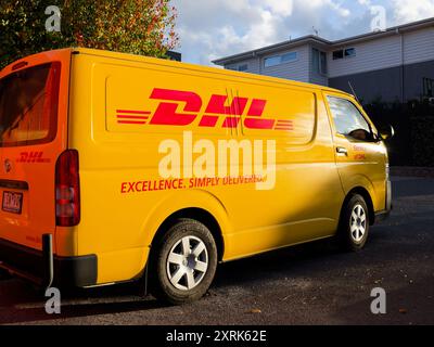 Gelber DHL-Lieferwagen mit Sonnenlicht, der spät an einem Herbsttag auf einem kleinen Parkplatz in der Vorstadt geparkt wurde Stockfoto