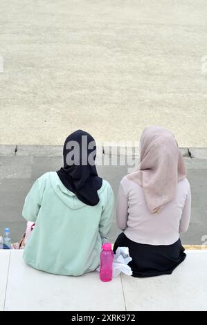 West-Java, Indonesien - 11. August 2024 : zwei Frauen mit Hijabs sitzen in einem Stadtpark in Tasikmalaya, West-Java, Indonesien. Stockfoto