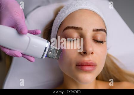 Gesichtsreinigung mit Ultraschall-Scrubber. Frau erhält Ultraschall-Gesichtspeeling und -Reinigung. Kosmetik- und Gesichtspflege. Gesichtsbehandlung Stockfoto