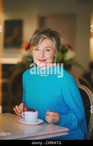 Porträt einer eleganten älteren 55- bis 60-jährigen Frau, die eine Tasse Kaffee in einem gemütlichen Café genießt Stockfoto