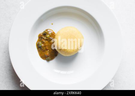 Blick von oben auf nigerianische Ogbono-Suppe und eba auf einem weißen Teller, Blick von oben auf Ogbono-Suppe mit garri und verschiedenen Fleischsorten auf einem Suppenteller Stockfoto