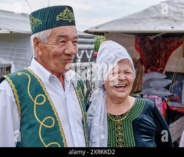 Tobolsk, Russland - 20. Juli 2024: Porträt eines glücklichen lachenden älteren asiatischen Paares in Nationalkleidung. Gäste des traditionellen tatarischen gastronomischen Festivals Stockfoto