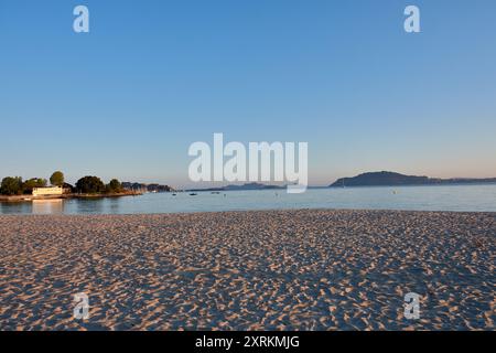 Die atemberaubende Schönheit der Playa de la Ladeira in Baiona bei Sonnenaufgang. Wenn die Sonne aufgeht, taucht ihr goldenes Licht den Sandstrand und das ruhige Wasser und schafft so Stockfoto