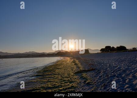 Die atemberaubende Schönheit der Playa de la Ladeira in Baiona bei Sonnenaufgang. Wenn die Sonne aufgeht, taucht ihr goldenes Licht den Sandstrand und das ruhige Wasser und schafft so Stockfoto