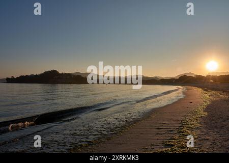 Die atemberaubende Schönheit der Playa de la Ladeira in Baiona bei Sonnenaufgang. Wenn die Sonne aufgeht, taucht ihr goldenes Licht den Sandstrand und das ruhige Wasser und schafft so Stockfoto