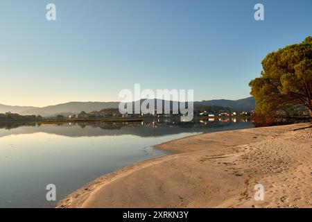 Die atemberaubende Schönheit der Playa de la Ladeira in Baiona bei Sonnenaufgang. Wenn die Sonne aufgeht, taucht ihr goldenes Licht den Sandstrand und das ruhige Wasser und schafft so Stockfoto