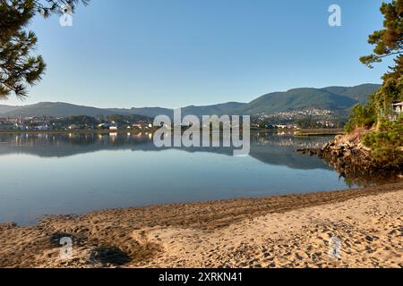 Die atemberaubende Schönheit der Playa de la Ladeira in Baiona bei Sonnenaufgang. Wenn die Sonne aufgeht, taucht ihr goldenes Licht den Sandstrand und das ruhige Wasser und schafft so Stockfoto