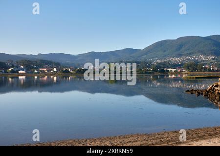 Die atemberaubende Schönheit der Playa de la Ladeira in Baiona bei Sonnenaufgang. Wenn die Sonne aufgeht, taucht ihr goldenes Licht den Sandstrand und das ruhige Wasser und schafft so Stockfoto