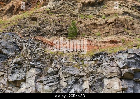 Verschiedene Gesteinsformationen aus Basalt, Sandstein, Schlacke und anderen Schichten in einem verlassenen Steinbruch Stockfoto