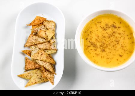 Kürbis-Karotten-Suppe mit Sahne und Pita-Brotchips auf weißem Hintergrund. Bokeh-Shot. Stockfoto
