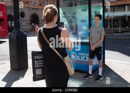 London, Großbritannien. August 2024. Am Sonntag, den 11. August 2024, machen die Leute Fotos von dem siebten neuen Kunstwerk des Street-Künstlers Banksy, das Piranha-Fische auf einer Polizeiwache in Ludgate Hill, City of London, London, England, zeigt. Foto: Justin ng/Alamy Live News Stockfoto