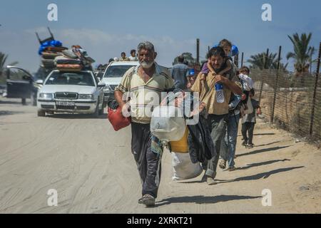 Khan Younis, Palästinensische Gebiete. August 2024. Die Palästinenser tragen ihre Sachen, als sie aus Hamad nach Al-Mawasi fliehen, nachdem die israelische Armee Flugblätter abgegeben hatte, in denen sie die Bewohner einer nördlichen Nachbarschaft in Khan Younis aufgefordert hatten, unmittelbar vor einer neuen Militäroperation im Gazastreifen zu evakuieren. Abed Rahim Khatib/dpa/Alamy Live News Stockfoto