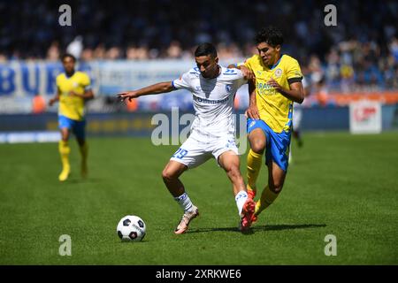 11. August 2024, Niedersachsen, Braunschweig: Fußball: Bundesliga 2, Eintracht Braunschweig - 1. FC Magdeburg, Spieltag 2, Eintracht-Stadion. Magdeburgs Livan Burcu (l) spielt gegen Braunschweiger Johan Gomez. Foto: Swen Pförtner/dpa - WICHTIGER HINWEIS: Gemäß den Vorschriften der DFL Deutschen Fußball-Liga und des DFB Deutschen Fußball-Bundes ist es verboten, im Stadion und/oder im Spiel aufgenommene Fotografien in Form von sequenziellen Bildern und/oder videoähnlichen Fotoserien zu verwenden oder zu verwenden. Stockfoto