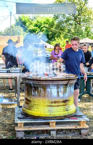 Zubereitung von Grillgerichten mit Stahlfelgen zum Kochen auf der Dorfmesse in Zentralfrankreich. Stockfoto