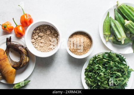 Overhead-Ansicht der Zutaten für die Zubereitung von Ogbono-Suppe auf einer Granitarbeitsfläche, Draufsicht der Miese und anstelle der Zutaten für die Zubereitung von Ogbono- und Okro-Suppe, Stockfoto