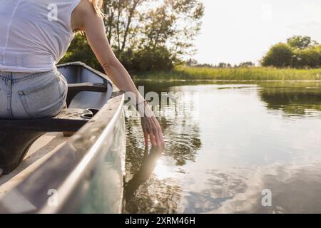 Frau genießt eine erstaunliche Sommer-Naturszene beim Kanufahren im See, Rückansicht. Kanu-Abenteuer und entspannende Konzepte. Stockfoto