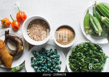 Overhead-Ansicht der Zutaten für die Zubereitung von Ogbono-Suppe auf einer Granitarbeitsfläche, Draufsicht der Miese und anstelle der Zutaten für die Zubereitung von Ogbono- und Okro-Suppe, Stockfoto