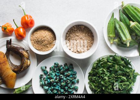 Overhead-Ansicht der Zutaten für die Zubereitung von Ogbono-Suppe auf einer Granitarbeitsfläche, Draufsicht der Miese und anstelle der Zutaten für die Zubereitung von Ogbono- und Okro-Suppe, Stockfoto