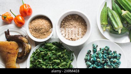 Overhead-Ansicht der Zutaten für die Zubereitung von Ogbono-Suppe auf einer Granitarbeitsfläche, Draufsicht der Miese und anstelle der Zutaten für die Zubereitung von Ogbono- und Okro-Suppe, Stockfoto