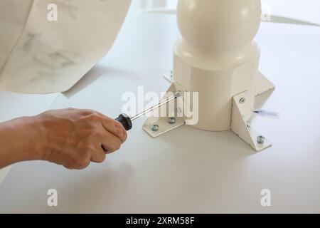 Asiatischer Mann, der weiße Tischmöbel zu Hause zusammenbaut Stockfoto