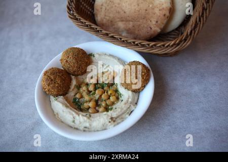 Hummus, Gericht aus dem Nahen Osten aus gekochten, pürierten Kichererbsen gemischt mit Tahini, Zitronensaft und Knoblauch, Pitabrot und frittierten Falafelbällchen Stockfoto