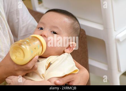 Ein Porträt des süßen neugeborenen Babys, das von ihrer Mutter mit Flasche, Liebe und Gesundheitskonzept gefüttert wird Stockfoto