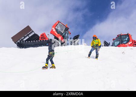 Elbrus, Russland - 01. August 2024: Bergsteiger üben ihre Kletterkünste auf einer verschneiten Piste mit Schneekatzen im Hintergrund Stockfoto