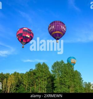 Farbenfrohe, sonnendurchflutete Ballons in der goldenen Stunde, von der Bristol Balloon Fiesta 2024, als sie über Bäume in der Nähe von Siston; Bristol passieren. Am Samstag um 45 Uhr Stockfoto