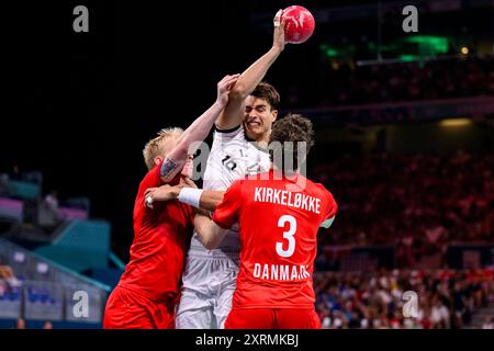 11. August 2024, Frankreich, Lille: Handball: Olympische Spiele, Deutschland - Dänemark, Endrunde, Finale, Stade Pierre-Mauroy. Deutschlands Julian Köster (Mitte) im Kampf gegen den Dänen Magnus Saugstrup (links) und den Dänen Niclas Kirkelokke (rechts). Foto: Tom Weller/dpa Stockfoto