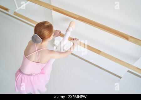 Ein junges Ballettmädchen beim Studiounterricht. Trainingsleistung. Stretching-Übungshaltung. Ballerina-Praxis-Balance-Technik. Klassische Eleganz Fitness. Tanzkostüm, Garn. Pinkfarbenes Kleid, Rock Stockfoto