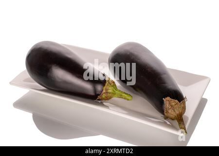 Zwei reife Auberginen auf einer weißen Keramikplatte, Makro, isoliert auf weißem Hintergrund. Stockfoto