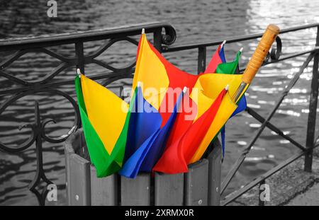 Annecy Lake nach Regen. Zerbrochener bunter Regenschirm in der Mülltonne. Retro-Foto mit schwarzem und weißem Hintergrund. Stockfoto