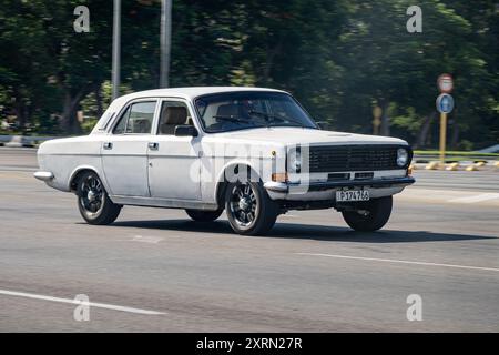 HAVANNA, KUBA - 27. AUGUST 2023: Weißes Wolga GAZ-24 russisches Auto in Kuba mit Bewegungsunschärfe Stockfoto