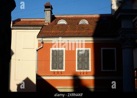 Im armenischen Innenhof in Lemberg steht ein leuchtend rotes Gebäude, das Schatten wirft, während das Sonnenlicht seine einzigartigen architektonischen Merkmale erleuchtet. Stockfoto
