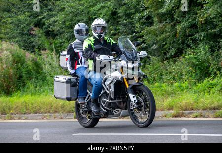 Potterspury, Northants, UK - 11. August 2024: Mann und Sozius fahren auf einem 2020 grünen Triumph Tiger Motorrad auf einer britischen Straße Stockfoto