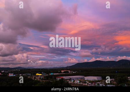 Ein atemberaubender Blick aus der Vogelperspektive, der einen pulsierenden Sonnenuntergang über der Landschaft von Phuket einfängt. Der Himmel ist voller leuchtender Gelb-, Orange-, Rosa- und Purpurtöne Stockfoto