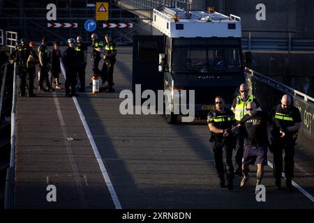 IJMUIDEN - Ein Gegendemonstrator wird von der Polizei weggenommen. Klimaaktivisten der Extinction Rebellion blockieren die Schleusen in IJmuiden. Sie warten auf das Kreuzfahrtschiff Seven Seas Mariner und blockieren die Passage für dieses Schiff. Einen Tag zuvor blockierten Demonstranten auch ein Kreuzfahrtschiff. Die Aktionsgruppe erklärt, dass sie mit dieser Aktion gegen die zerstörerischen Auswirkungen der Kreuzfahrt auf das Klima demonstrieren. ANP RAMON VAN FLYMEN niederlande aus - belgien aus Stockfoto