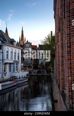 Turm der Kirche unserer Lieben Frau und altes Fachwerkhaus am Kanal in Brügge, Belgien. Stockfoto