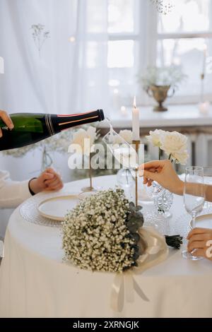 Kellnerin gießt Champagner aus der Flasche in ein Glas im Restaurant. Feierliche Veranstaltung Stockfoto