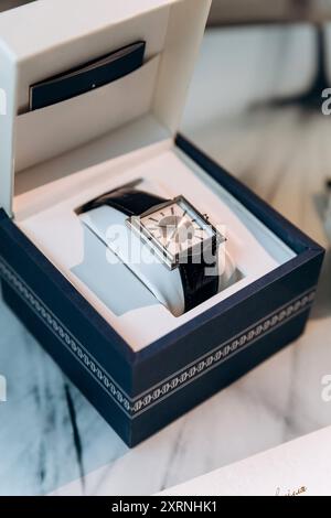 Die wichtigsten Hochzeitsartikel des Bräutigams auf dem Tisch, darunter Ringe am Telefon, Fliege, Boutonniere, Parfüm und Gürtel Stockfoto